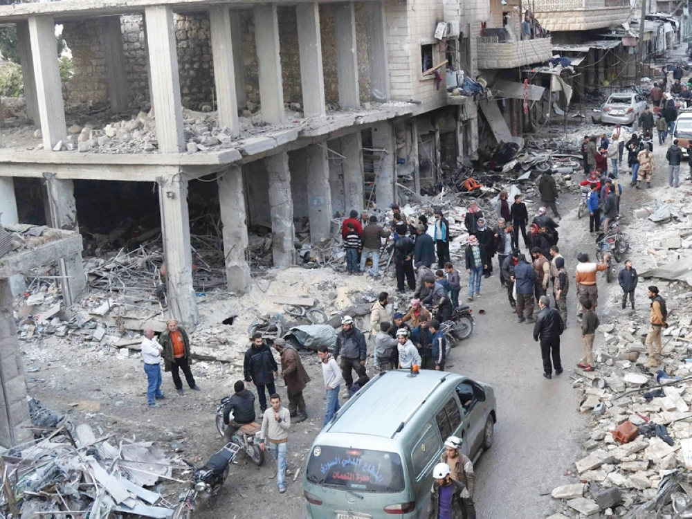 سوريون يبحثون عن ناجين جراء غارة جوية من النظام على معرة النعمان بإدلب أمس (أ ف ب)