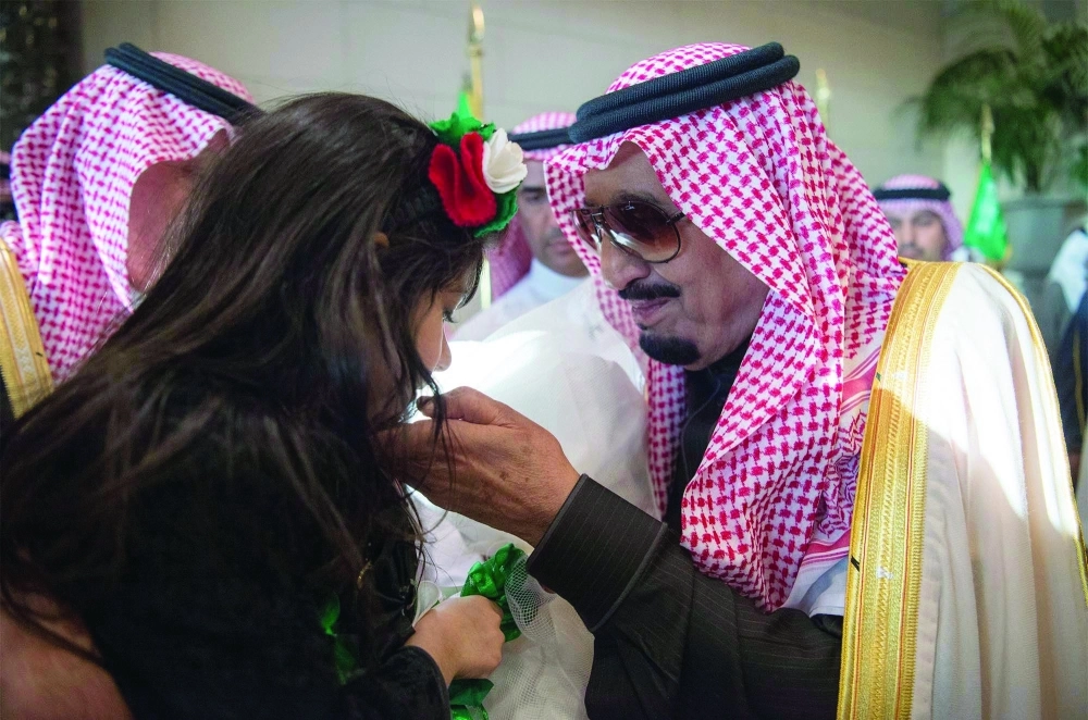 الملك سلمان مداعبا طفلة قدمت له باقة ورد
