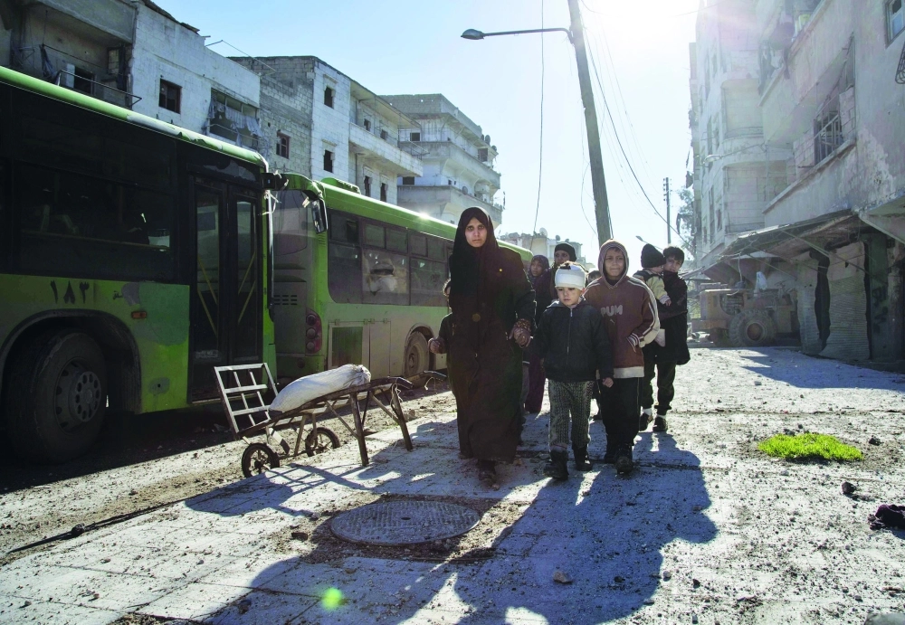 أسرة سورية في طريقها لحافلة إجلاء من حلب أمس                                               (أ ف ب)
