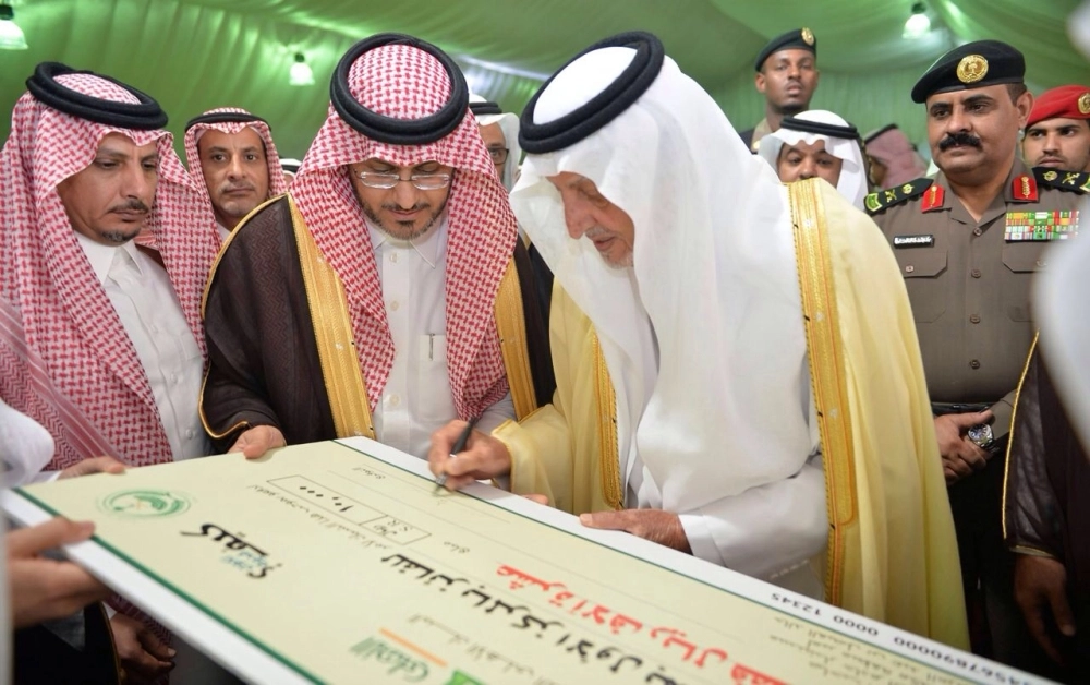 خالد الفيصل موقعا على شيك لأحد الطلبة المكرمين 