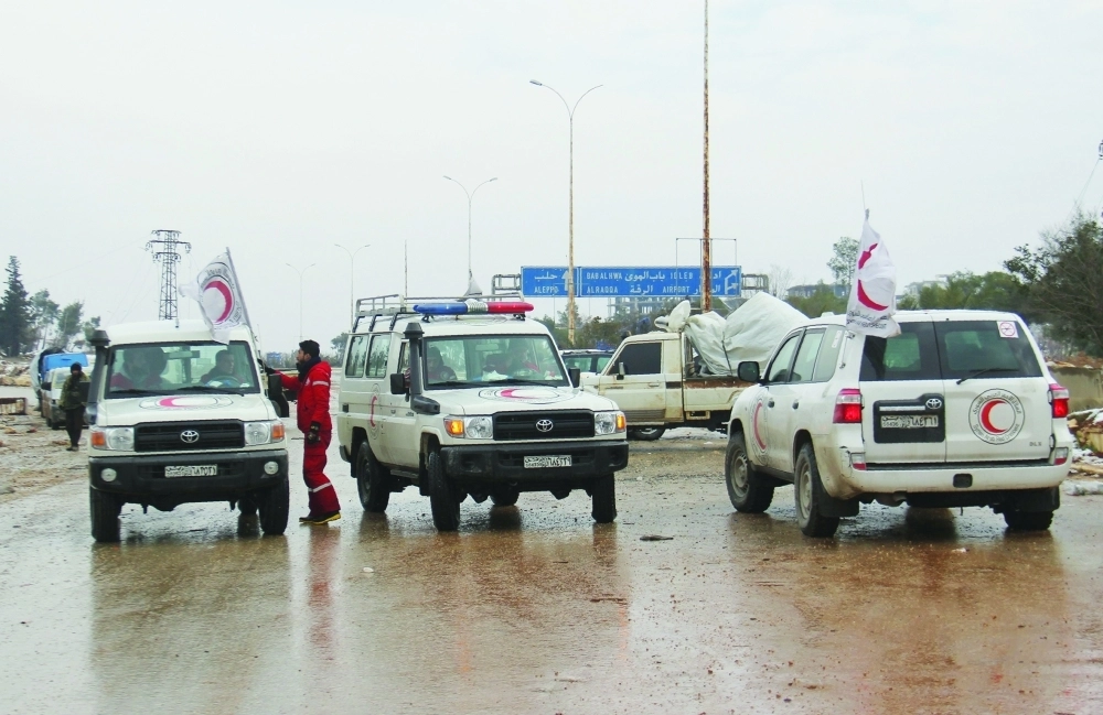 موظفون بالهلال الأحمر ينتظرون على الطريق قرب الراشدين غرب حلب (أ ف ب)