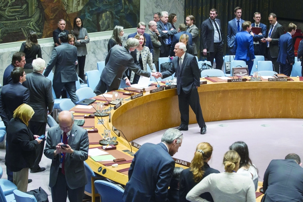 سفير فلسطين بالأمم المتحدة يصافح نظيره الإسباني بعد التصويت على قرار مجلس الأمن                         (أ ف ب)