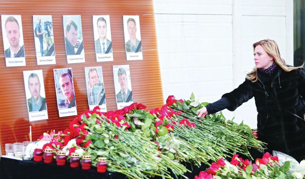 سيدة تضع زهورا قرب صور لضحايا الطائرة في موسكو                        (إ ب أ)