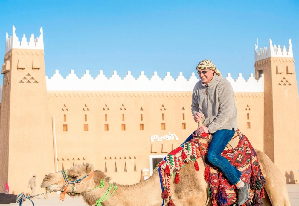 زائر أجنبي يمتطي جملا في جناح القصيم                                                          (واس)