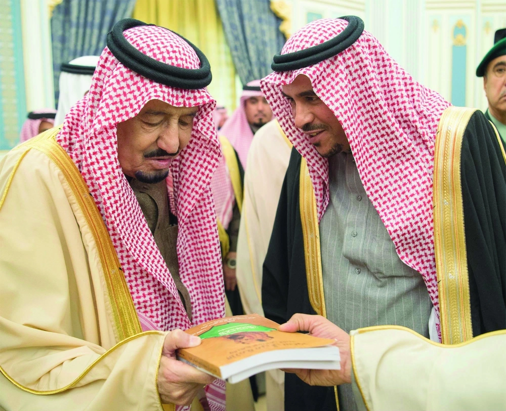 الملك سلمان مطلعا على كتاب قدمه له أحد الضيوف
