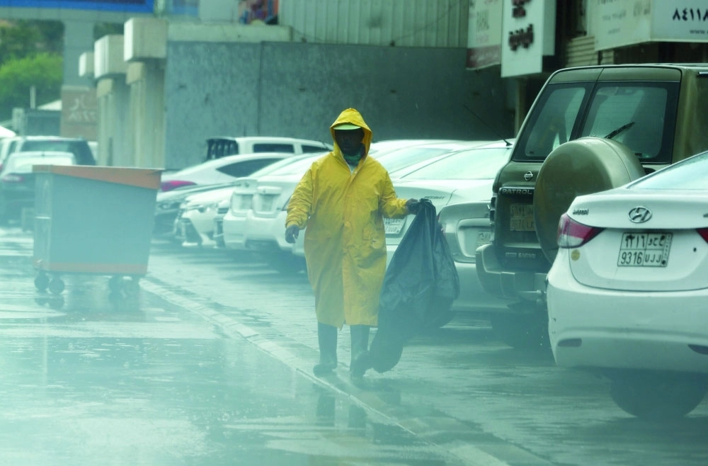 عامل نظافة يواصل عمله تحت المطر  