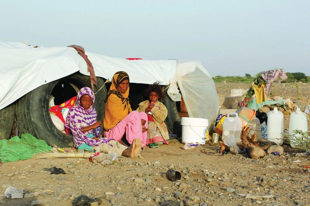 يمنية وابنتاها أمام كوخ في مخيم موقت للاجئين في منطقة الجراحي بالحديدة أمس                               (رويترز)