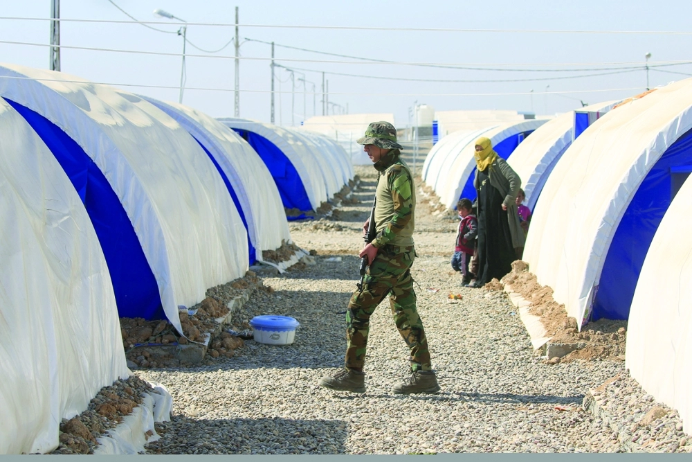جندي عراقي يسير وسط مخيم لاجئين جنوب الموصل (رويترز)