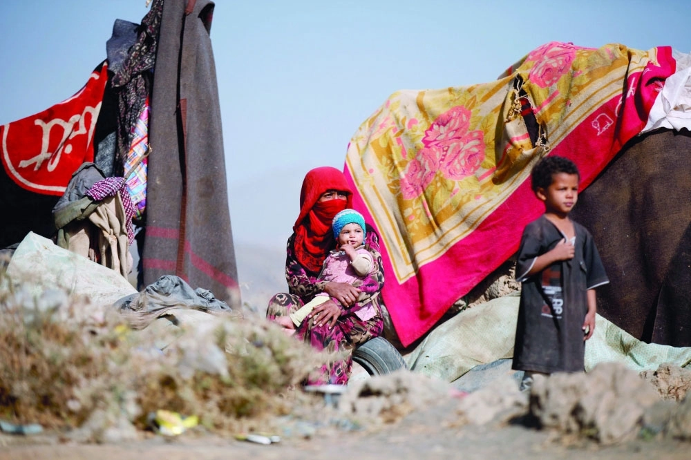 يمنية تجلس مع أطفالها في مخيم للنازحين بمنطقة ضروان في مديرية همدان                                             (رويترز) 