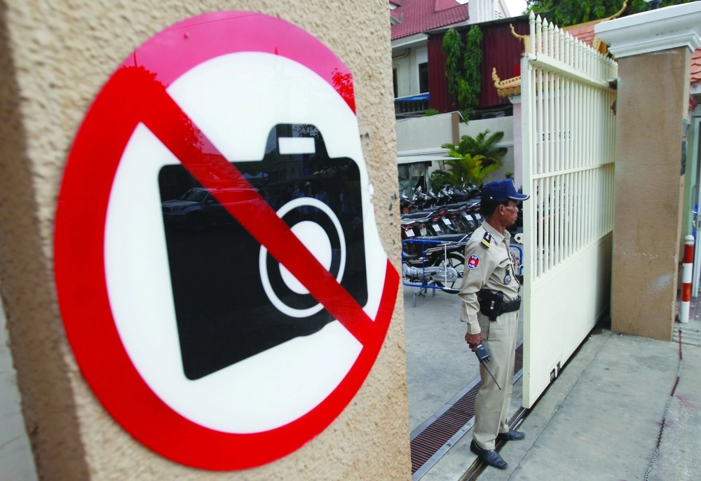 شرطي كمبودي يقف بجوار ملصق يحذر من حمل أجهزة الكترونية بمطار بنوم بنه                                     (إ ب أ)