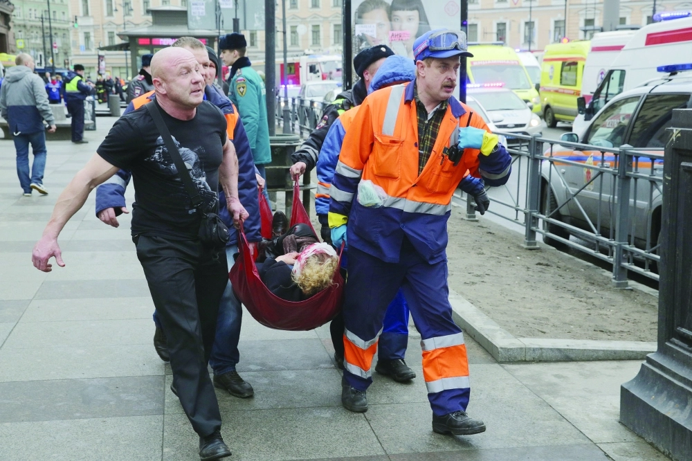 مسعفون يحملون مصابا بالتفجير أمس