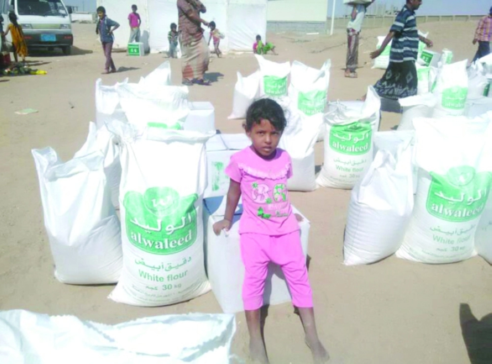 طفلة يمنية بالمخا تقف بجوار أكياس طحين من مركز الملك سلمان                                       (واس)