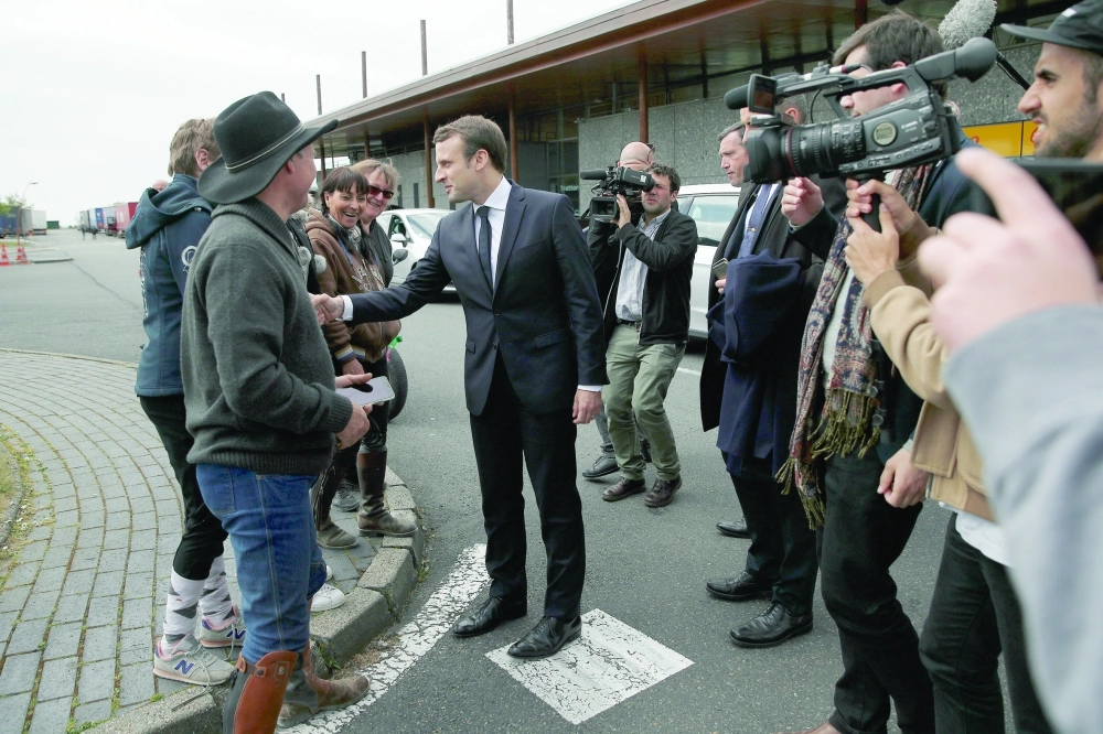 ماكرون أبرز المرشحين يصافح عددا من الناخبين عقب الإدلاء بصوته أمس                                                                                 (إ ب أ)
