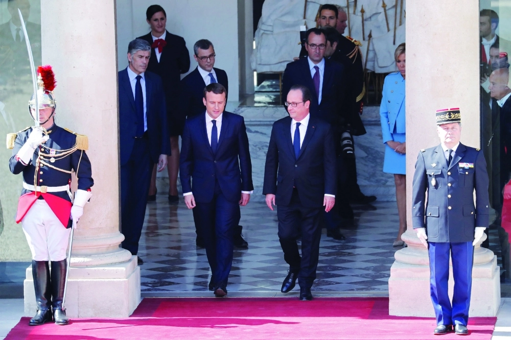 إيمانويل يرافق الرئيس السابق هولاند خلال مغادرته الإليزيه              (رويترز)