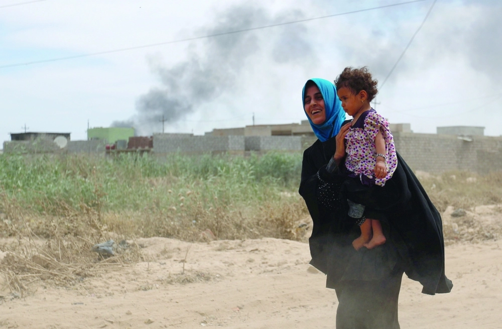 نازحة عراقية تحمل ابنتها هربا من القتال غرب الموصل   (رويترز)