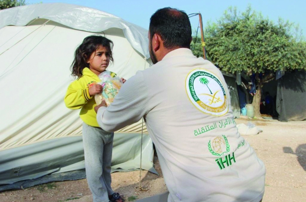أحد منسوبي الحملة السعودية يسلم طفلة سورية خبزا            (واس)