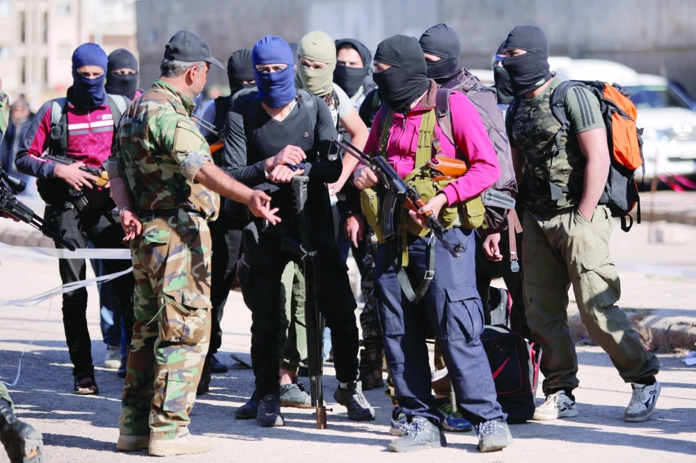 عدد من مسلحي المعارضة السورية لحظة خروجهم من حي الوعر بحمص أمس الأول                     (رويترز)