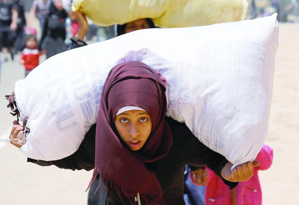 A Syrian girl, who says she is returning to Syria ahead of the Eid al-Fitr, carries her belongings as she walks to the Turkish Cilvegozu border gate, located opposite of Syrian crossing point Bab al-Hawa in Reyhanli, in the southern Hatay province