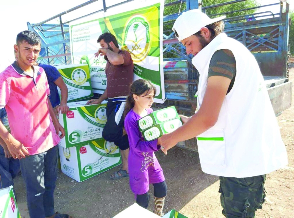 لاجئة سورية تتسلم وجبات إفطار سعودية     (واس)