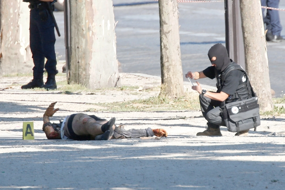 شرطي فرنسي يصور جثة الإرهابي في حادث الشانزليزيه أمس                                           (رويترز)