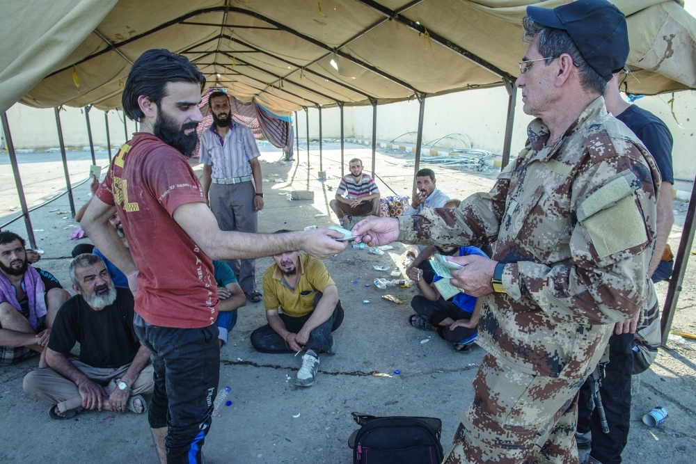 عراقي هارب من قتال داعش يتسلم أوراقا ثبوتية من الجيش بالموصل                                                                         (د ب أ)