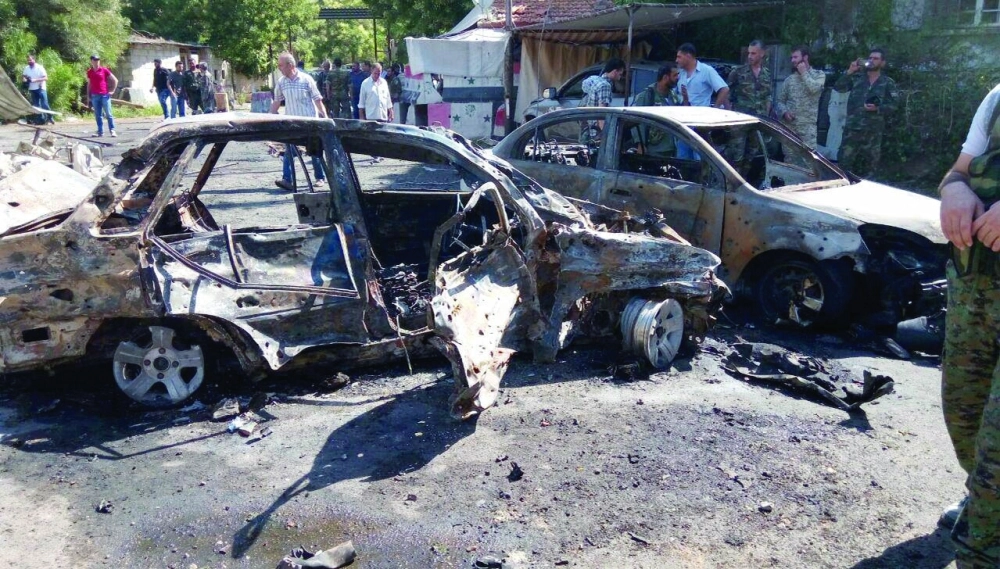 تجمع سوريين حول بقايا السيارتين المفخختين في دمشق أمس                                                             (د ب أ)