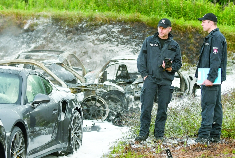 أفراد من الشركة بجانب سيارات متضررة              (د ب أ)