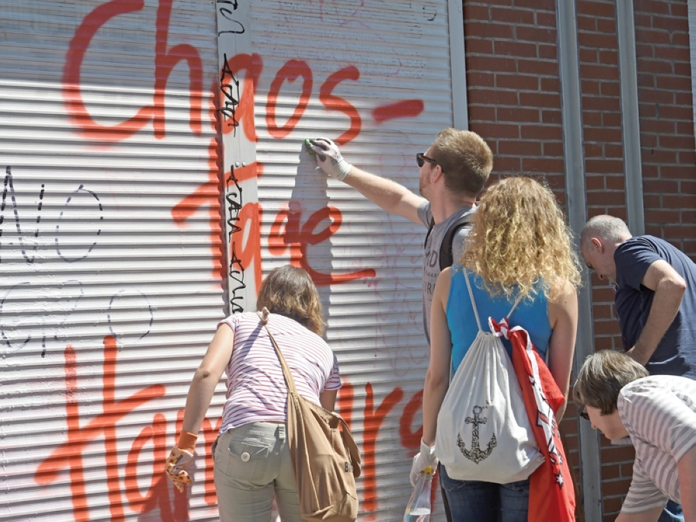 ألمان ينظفون واجهة محل كتب عليه (أيام الفوضى في هامبورغ) أمس  (رويترز)