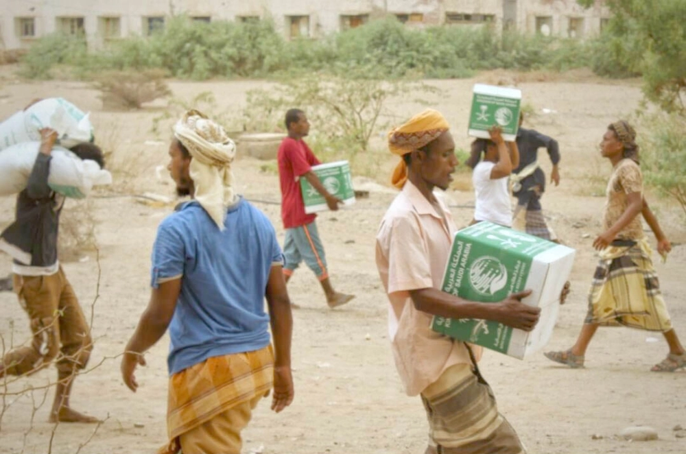 يمنيون يحملون مساعدات من مركز الملك سلمان في لحج (واس)