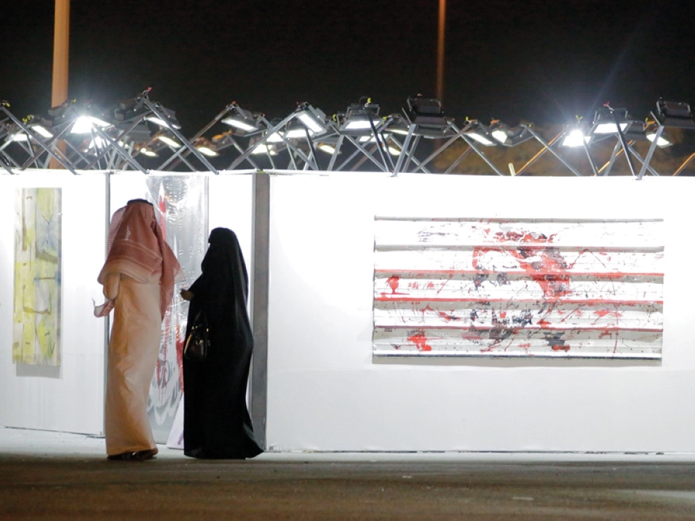 زوار يتأملون جدارية الفن التشكيلي في سوق عكاظ أمس (شاكر بيك)