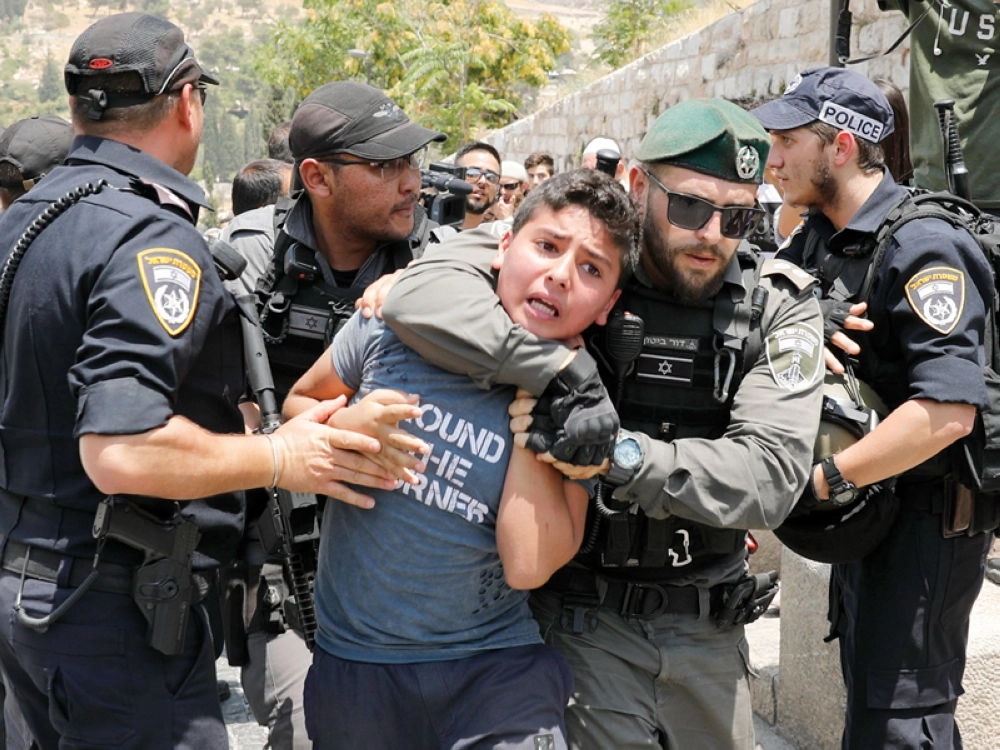 جندي إسرائيلي يعتقل شابا فلسطينيا تظاهر مع المئات أمام الأقصى (إ ب أ)