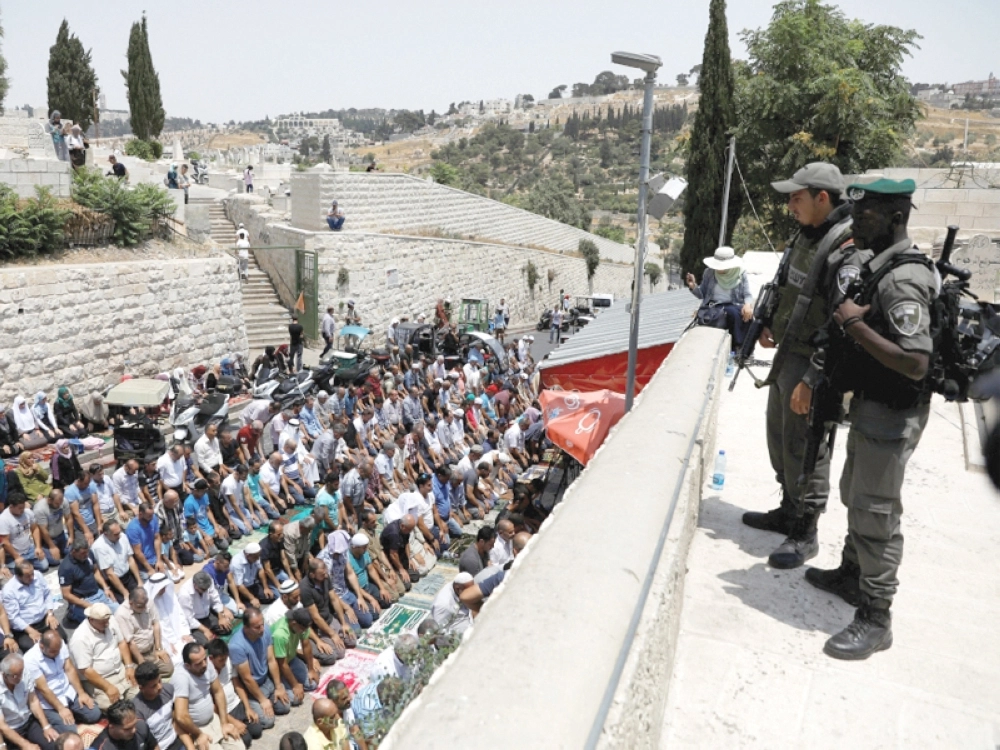 قوات الاحتلال تراقب فلسطينيين يصلون على مدخل البلدة القديمة في القدس (روتيرز)
