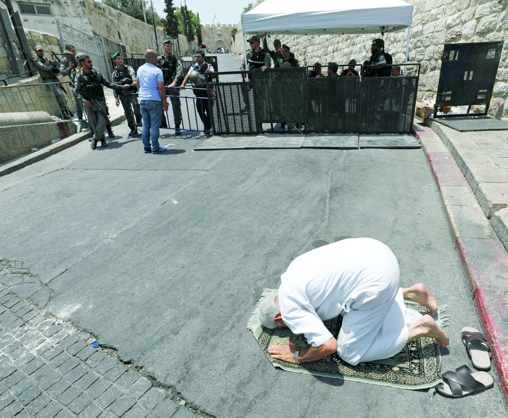 فلسطيني يصلي خارج الأقصى بعد منعه من الصلاة داخل المسجد (رويترز)