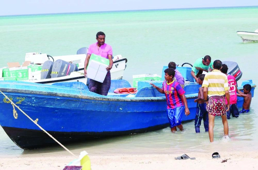 يمنيون يفرغون قوارب محملة بمساعدات غذائية من مركز الملك سلمان لجزيرتي الفشت وبكلان في محافظة جدة اليمنية (واس)
