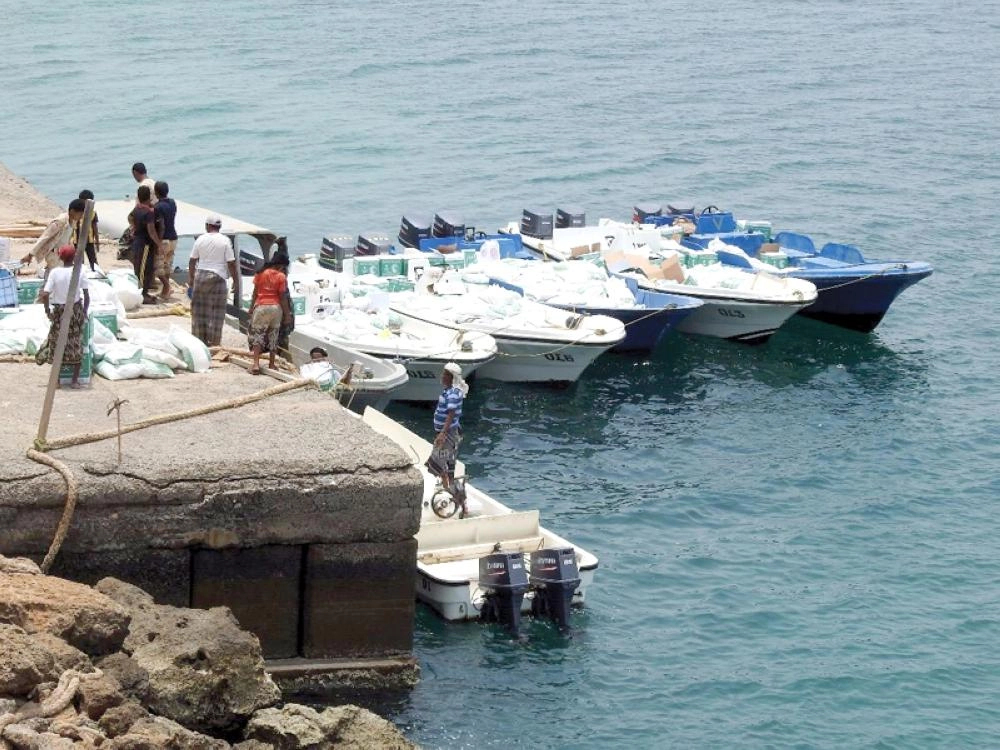 يمنيون يفرغون قوارب محملة بمساعدات غذائية من مركز الملك سلمان لجزيرتي الفشت وبكلان في محافظة جدة اليمنية (واس)