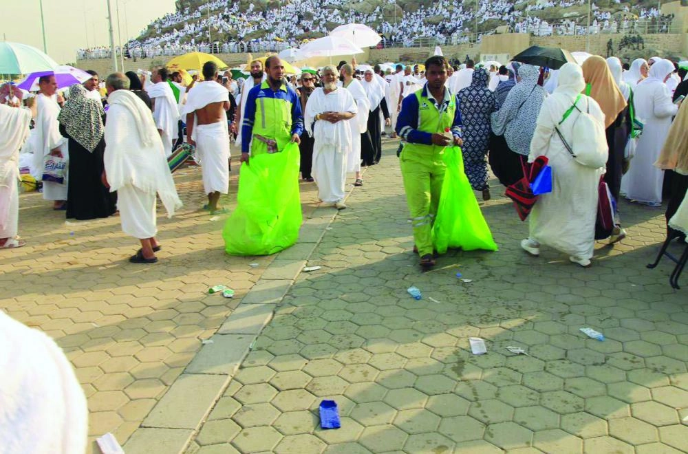 عمال نظافة في مشعر عرفات يجمعون النفايات أمس             (واس)