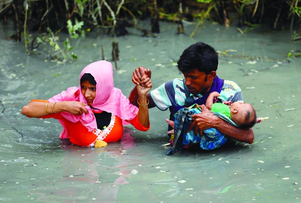 روهينجي وأسرته يسيرون في المياه بعد عبورهم حدود ميانمار إلى بنجلاديش (رويترز)