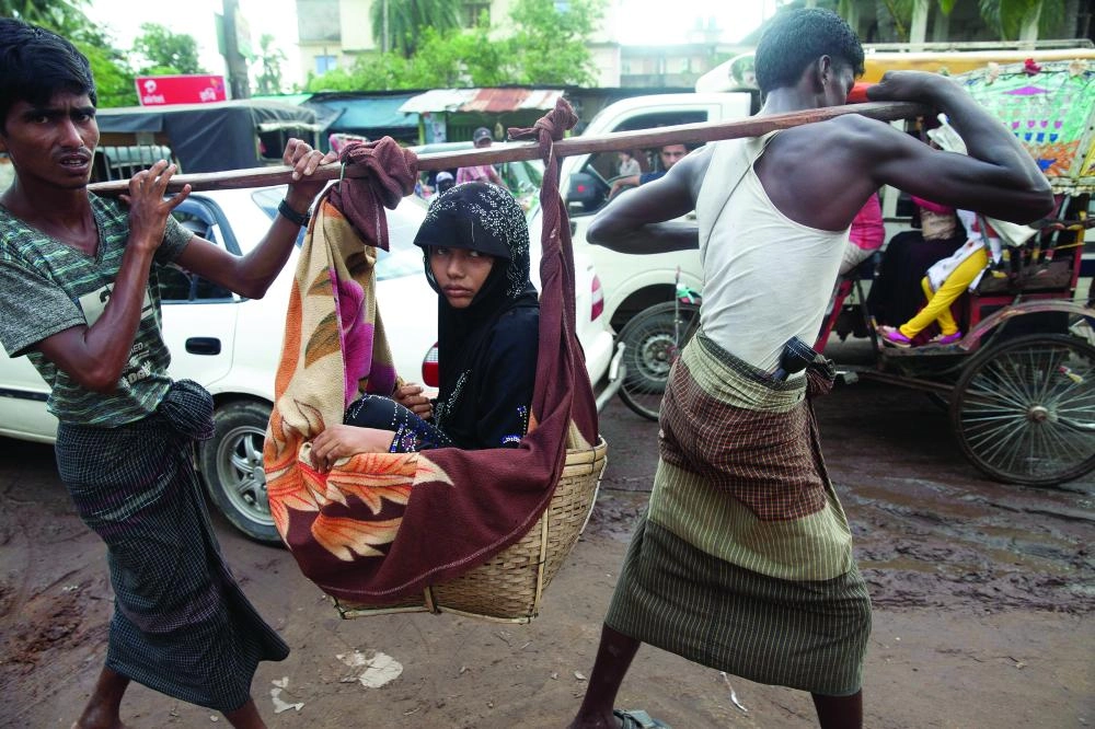 رجلان يحملان فتاة مقعدة بعد عبورهم حدود ميانمار إلى بنجلادش (إ ب أ) 