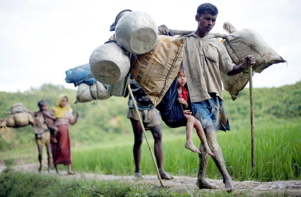 






روهينجي يحمل أغراضه وطفله هربا من العنف في ميانمار              (رويترز)
