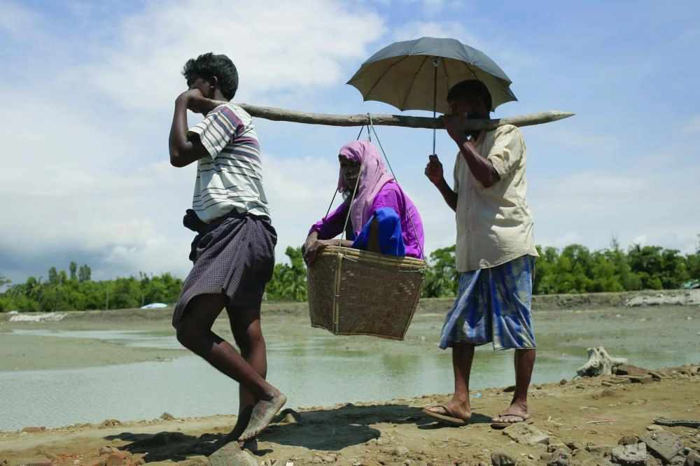 






روهينجيان يحملان مسنة خلال هروبهم من العنف في ميانمار                                                                                     (د ب أ) 