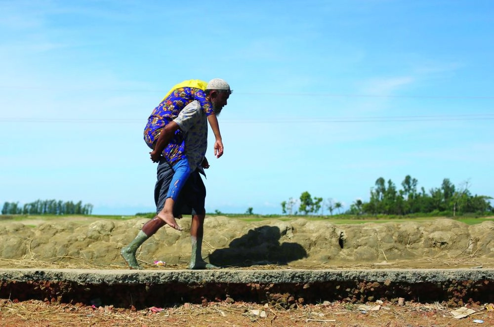 A Rohingya refugee man carries a woman after crossing the Bangladesh-Myanmar border by boat through the Bay of Bengal in Shah Porir Dwip, Bangladesh, September 15, 2017. REUTERS/Danish Siddiqui