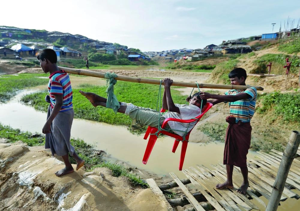 






روهينجيون يحملون رجلا ضربه جنود ميانمار لدى وصولهم بنجلاديش                             (رويترز)