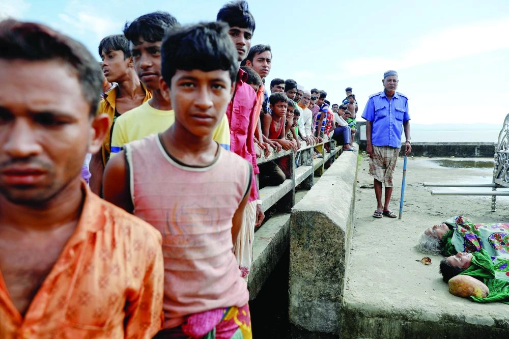 






روهينجيون بجانب جثامين غرقى قارب يحمل لاجئين من ميانمار                                   (رويترز)