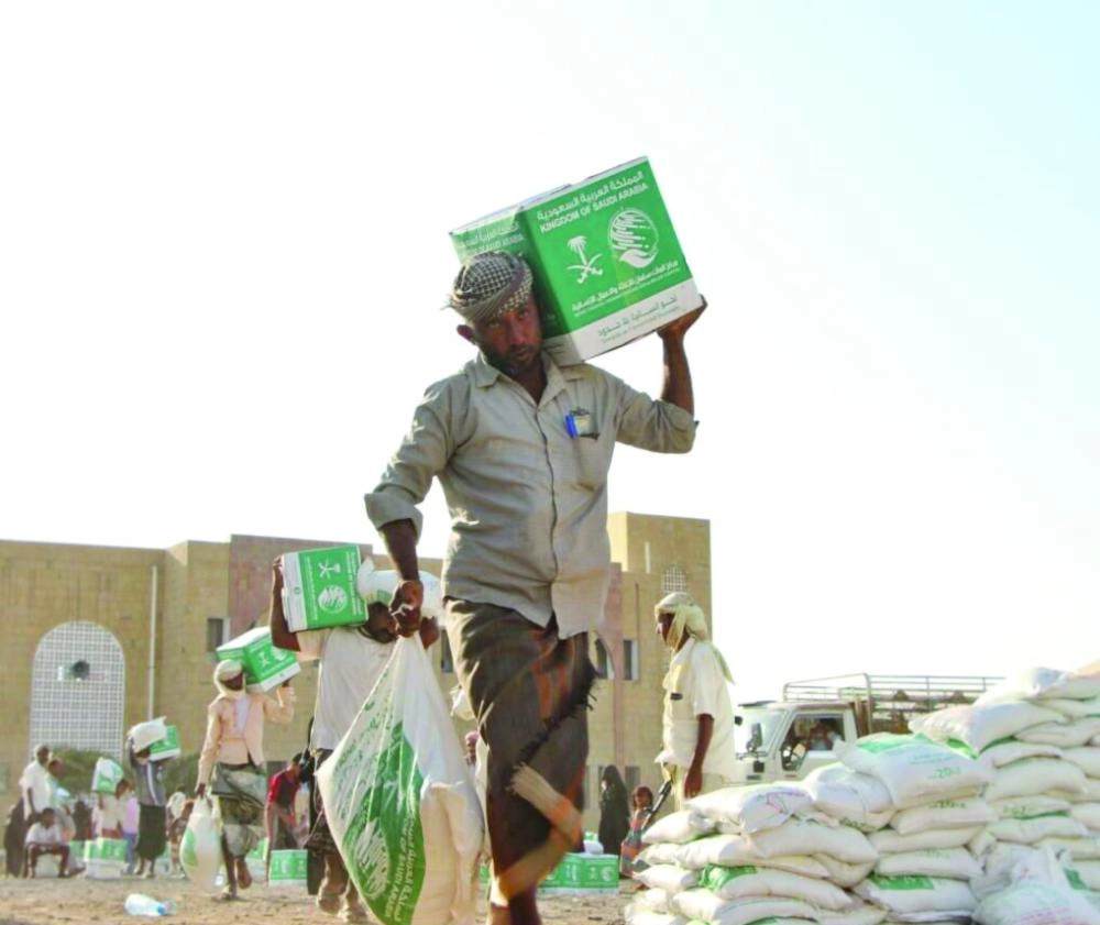 يمنيون في المخا يحملون سلالا غذائية من مركز الملك سلمان (واس)