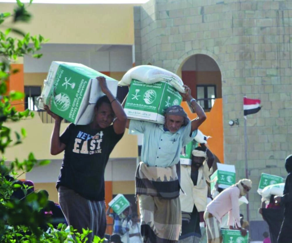 يمنيون في المخا يحملون سلالا غذائية من مركز الملك سلمان (واس)