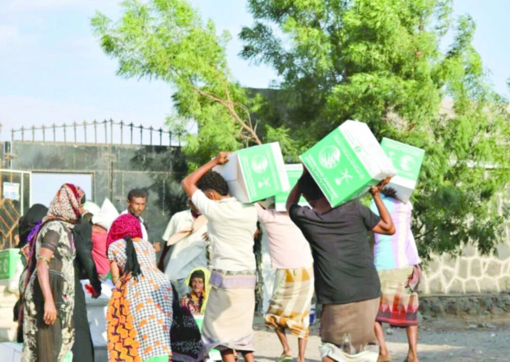 يمنيون في المخا يحملون سلالا غذائية من مركز الملك سلمان