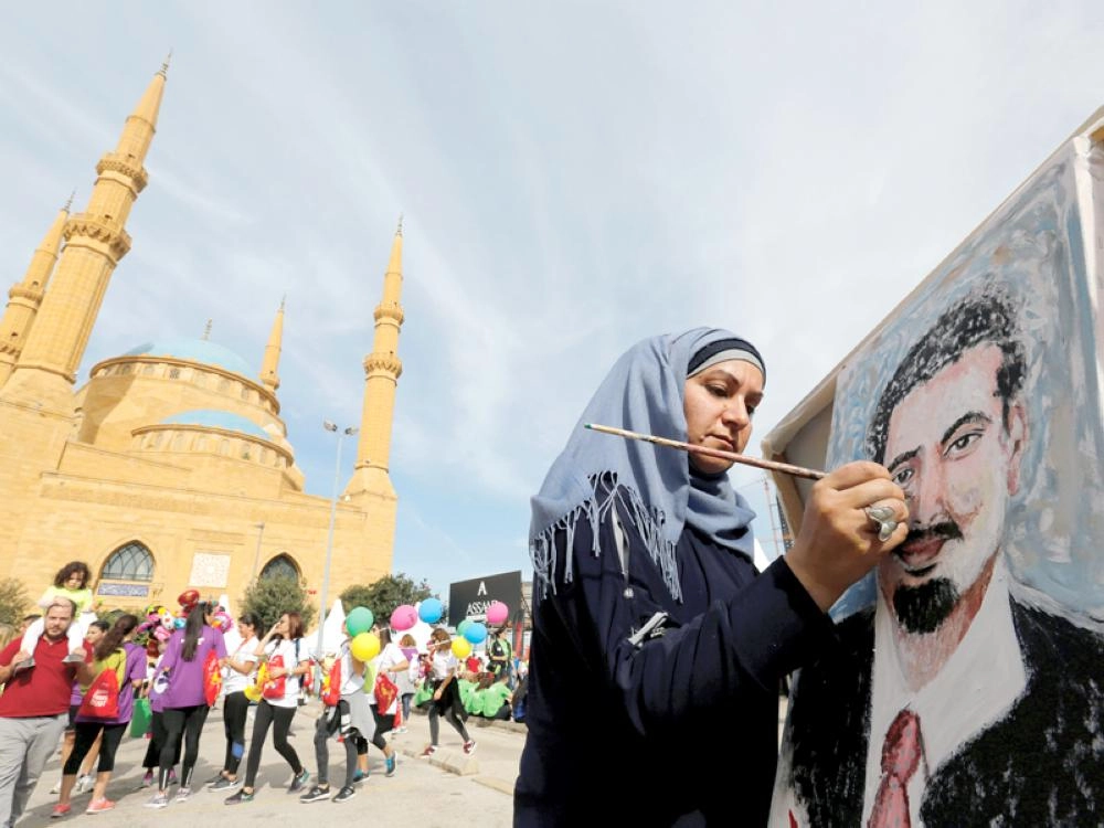 فنانة لبنانية ترسم بورتريه للحريري على هامش ماراثون بيروت أمس (رويترز)