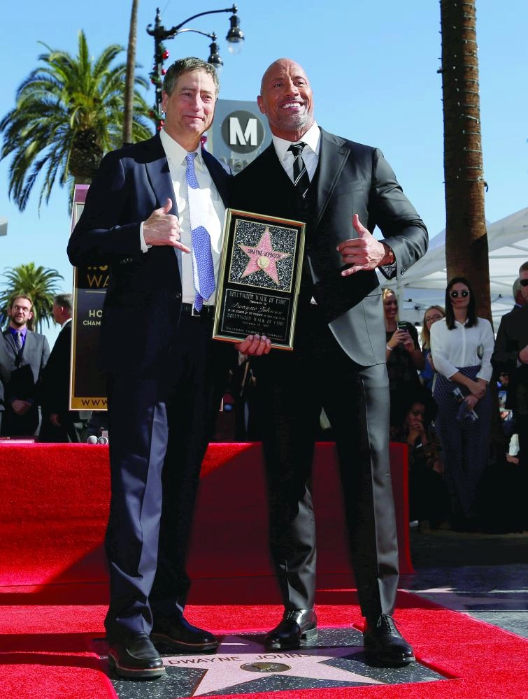 Actor Dwayne Johnson (R) poses on his star with Thomas Rothman, chairman of Sony Pictures Entertainment's Motion Picture Group, after it was unveiled on the Hollywood Walk of Fame in Los Angeles, California, U.S., December 13, 2017. REUTERS/Mario Anzuoni