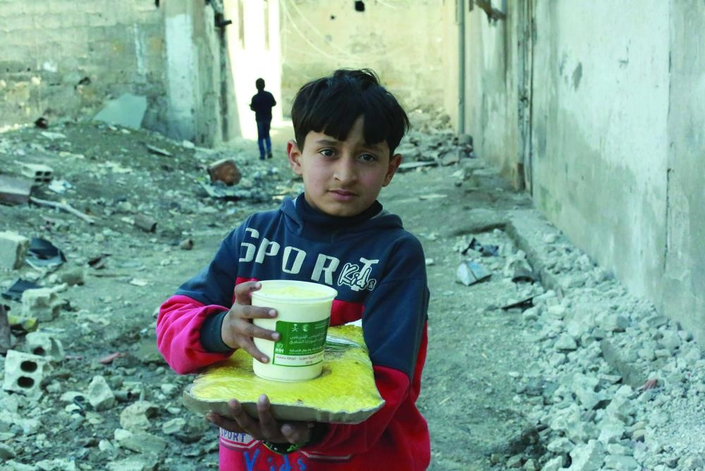 طفل سوري بالغوطة الشرقية يحمل وجبة سعودية