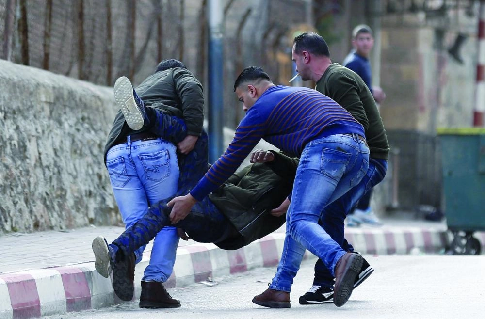 






فلسطينيون ينقلون مصابا في المواجهات أمس                         (د ب أ)